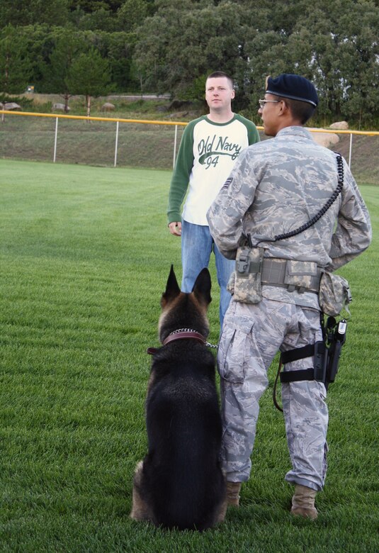 Members of the 21st Security Forces Squadron prepare to demonstrate apprehension tactics with one of their military working dogs for guests at the Deployed Families Dinner, hosted by Cheyenne Mountain Air Force Station Aug. 6. The event brought out nearly 120 guests despite thunderstorms and heavy rains, which cleared up as the event kicked off. (U.S. Air Force photo)