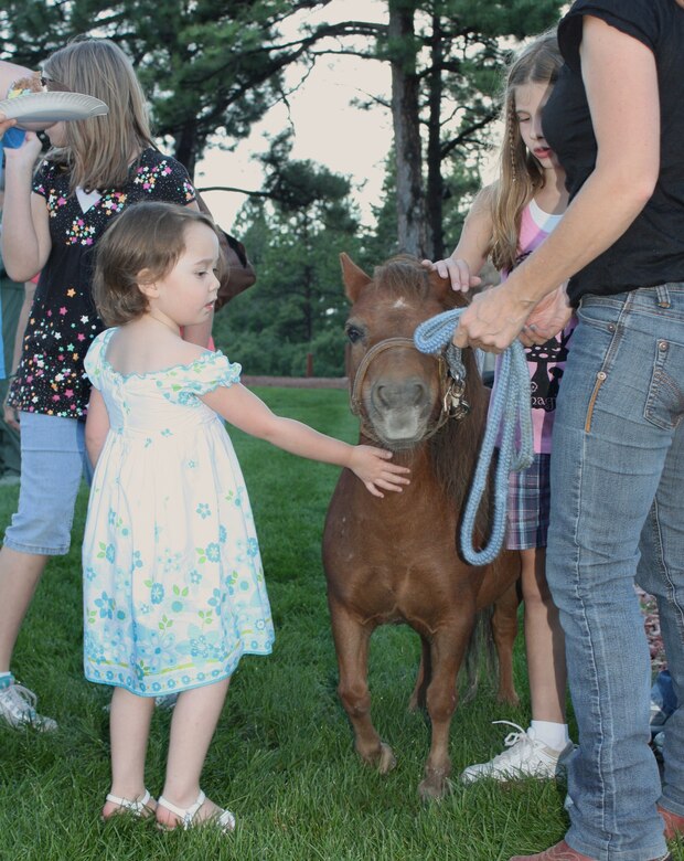 A young girl pets a miniature horse brought to the Deployed Families Dinner hosted by Cheyenne Mountain Air Force Station Aug. 6. Jackie Brusseau, 721st Mission Support Group contractor, along with her daughter, brought their two miniature horses for guests to pet and photograph. This was the first time the DFD was held at CMAFS. (U.S. Air Force photo)