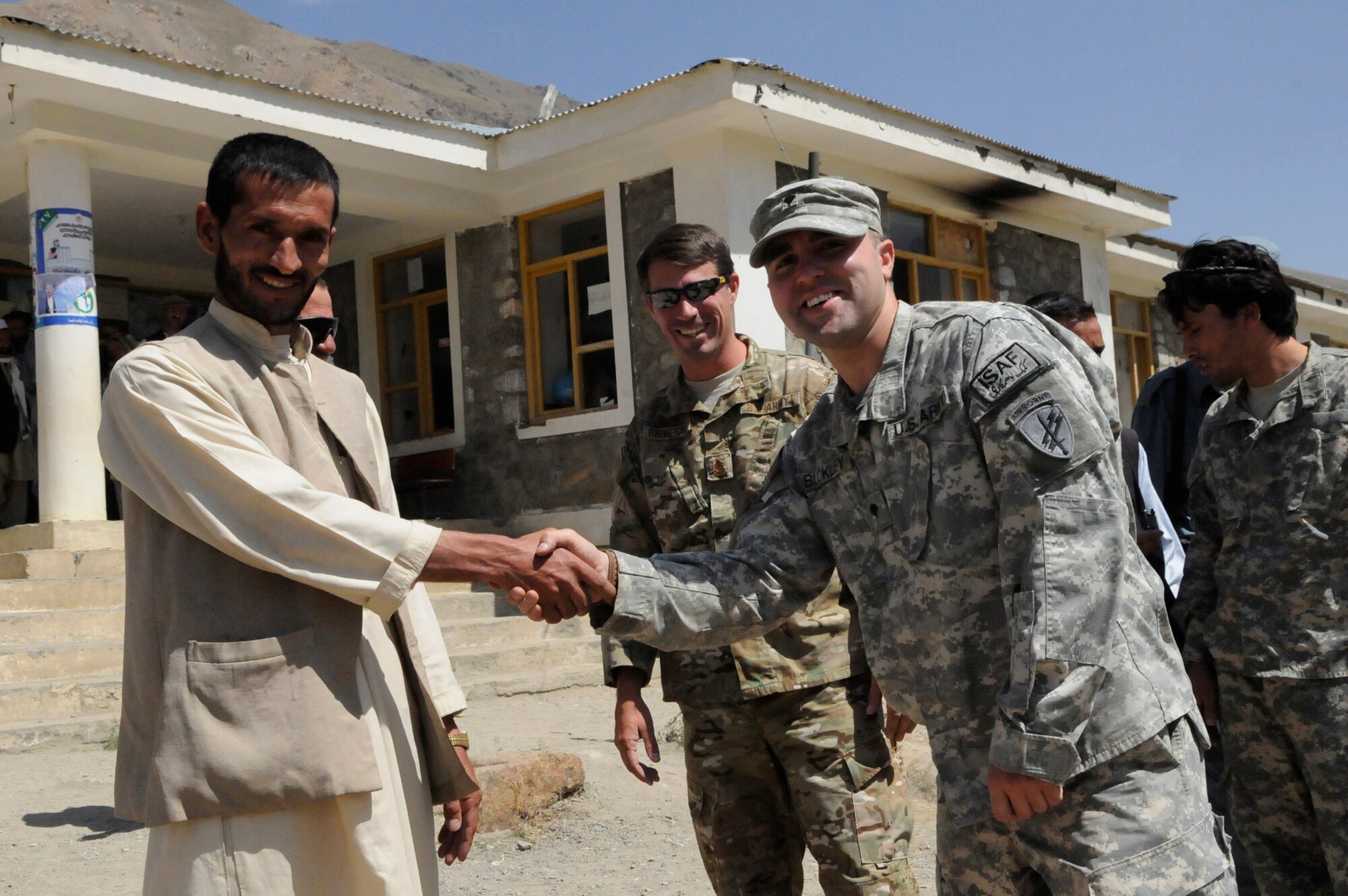 The principal of the Kur Petab boys middle school, Khenj District, expresses his gratitude after U.S. Army Master Sgt. Chad Rhinehart of Washington, N.J., Provincial Reconstruction Team Panjshir?s civil affairs noncommisioned officer in charge and U.S. Army Spc. Christopher Buckley of Old Bridge, N.J., Provincial Reconstruction Team Panjshir?s civil affairs team members handed out notebooks to students who attend the Kur Petab boys middle school in Khenj District.  The notebooks were donated by numerous friends and family members of Team Panjshir.  (U.S. Air Force photo by: Tech. Sgt. Sean Mateo White PRT Panjshir photographer)   