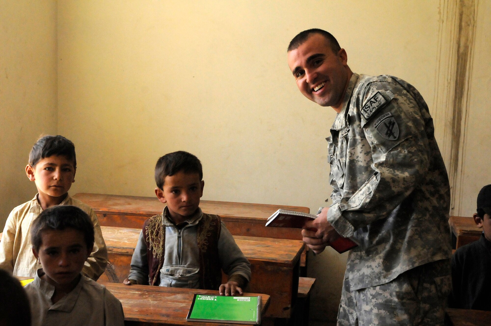 U.S. Army Spc. Christopher Buckley of Old Bridge, N.J., Provincial Reconstruction Team Panjshir?s civil affairs team member, hands out notebooks to students who attend the Kur Petab boys middle school in Khenj District.  The notebooks were donated by numerous friends and family members of Team Panjshir.  (U.S. Air Force photo by: Tech. Sgt. Sean Mateo White PRT Panjshir photographer)   