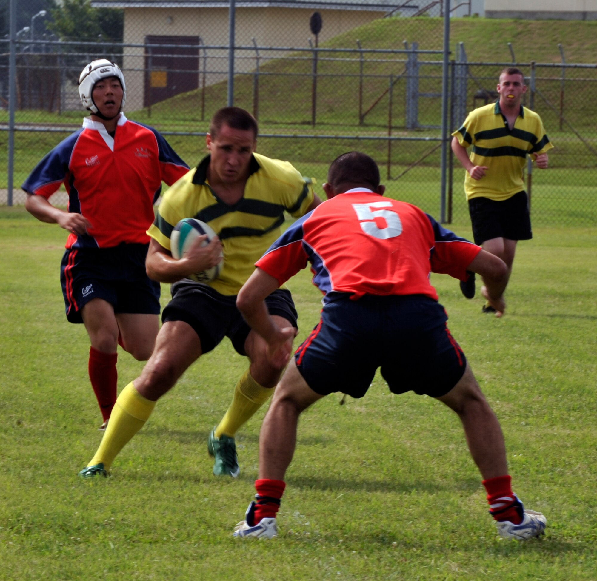 Misawa Snow Devils rugby player Matthew Duggan, center, prepares to juke Tetsu Hosono, right, while Snow Devil, Jon Leonard, back right, prepares to support during a game at Misawa Air Base, Japan, Aug. 29.  Keisuke Ryu, left, chases Matt after the missed tackle. The Snow Devils hosted bi-lateral rugby games against the Japan Air Self Defense Force rugby team. The teams played two games; the first game was a Snow Devils victory 24-17. The second was two teams of Snow Devils and JASDF players, combined, bi-laterally competing against one another.  (U.S. Air Force photo/Tech. Sgt. Russell McBride/released) 

