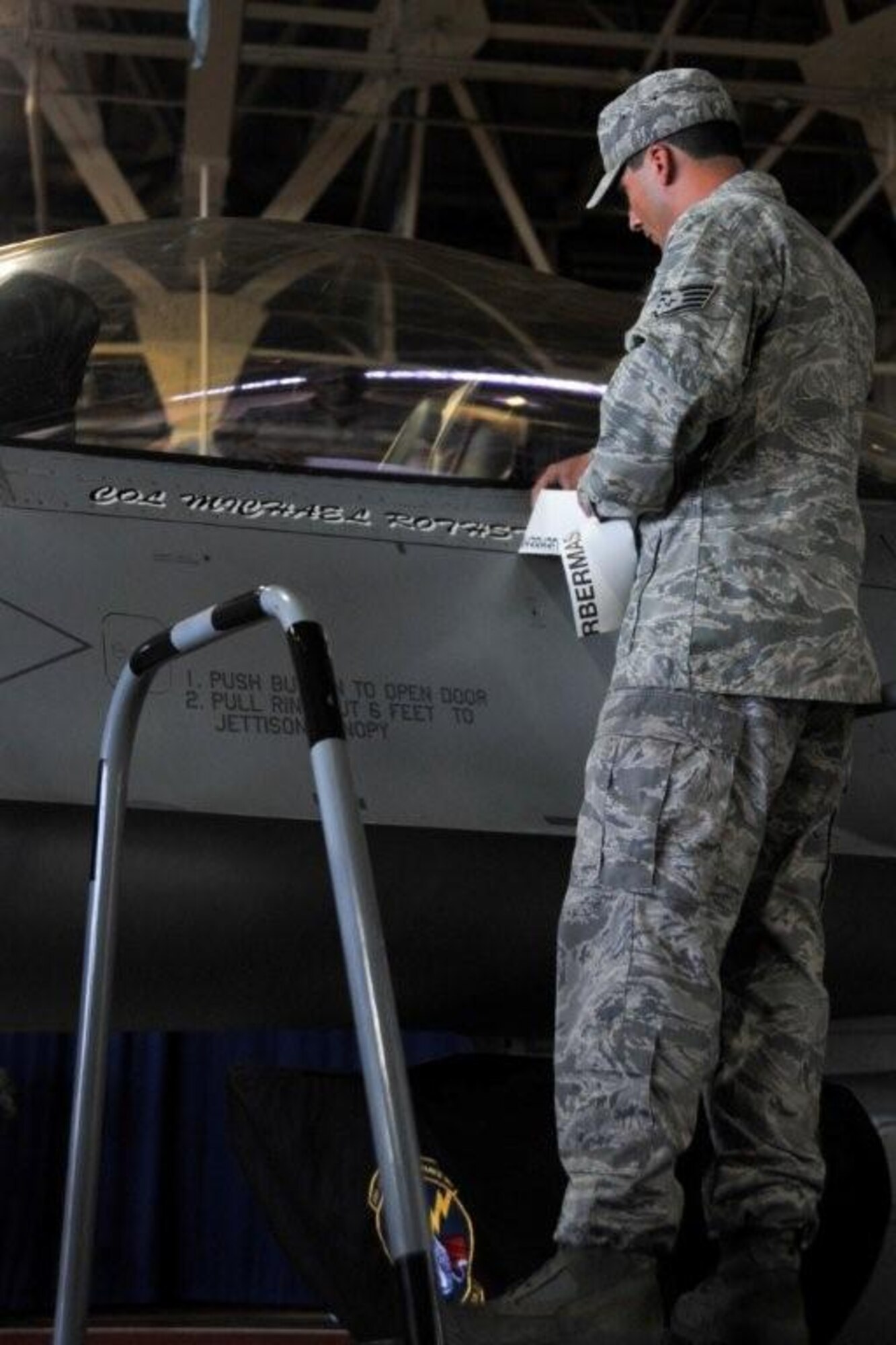 U.S. Air Force Staff Sgt. Robert Randolph, 13th Aircraft Maintenance Unit crewchief, unveils the name printed below the canopy of the wing's flagship F-16 Fighting Falcon to reflect the new wing commander during an assumption of command ceremony, in Hangar 949 at Misawa Air Base, Japan, Aug. 31, 2010. The new installation and wing commander, Col. Michael D. Rothstein is a command pilot with more than 2,400 flying hours. (U.S. Air Force photo by Tech. Sgt. Russell McBride/Released)
