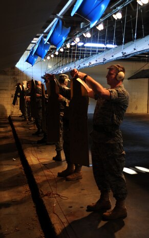 Shooters attach their targets at the 25-meter mark for their final magazine at the Combat Arms Training and Maintenance range facility's opening ceremony Aug. 31, 2010, on Joint Base Charleston, S.C. The improved range has 30 fans that blow gun smoke down and out the range, making it well ventilated so instructors and students don't inhale the smoke. The new and improved range also includes spotlights to illuminate targets down the range. (U.S. Air Force photo/Senior Airman Timothy Taylor)