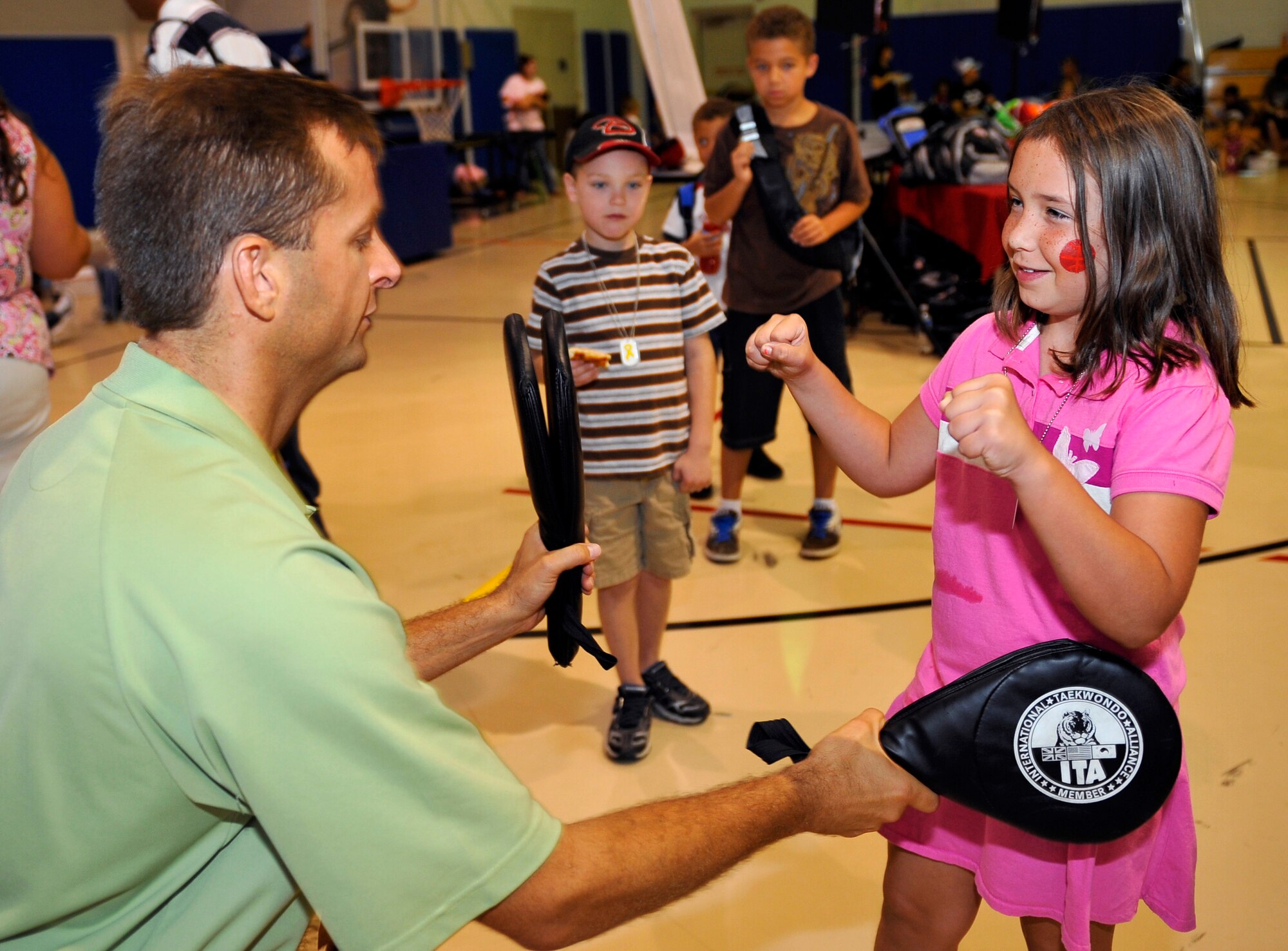 HOLLOMAN AIR FORCE BASE, N.M. -- David Overstreet signals Kimberly Marquez, daughter of Tech Sgt. Dennis Markham, 49th Maintenance Group, when to throw a right and left punch at a "focus" pad during the Young Heroes Deployment Expo Aug. 28, 2010. Children enjoyed learning self defense with David Overstreet's Taekwondo focus pads and blockers at the expo.  Also provided were carnival games, bouncy castles, free pizza and a hero-pack ceremony where they gave Holloman's youngest heroes a care package, dog tags and a certificate of appreciation. (U.S. Air Force photo by Senior Airman Veronica Stamps / Released)