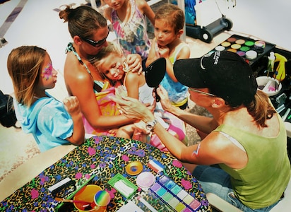 Held by her mother Vanessa Drew, Natalie Drew gazes in a mirror as children gather round to see her finished face painting at the base pool on Joint Base Charleston, S.C., Aug. 28, 2010. The kaleidoscope of paints was an instant hit at the finale, producing bright eyes and colorful cheeks for children playing in the summer heat. Vanessa is the wife of U.S. Air Force Staff Sgt. Matthew Drew who is a weather forecaster with the 437th Operations Support Squadron. (U.S. Air Force photo/Staff Sgt. Daniel Bowles)