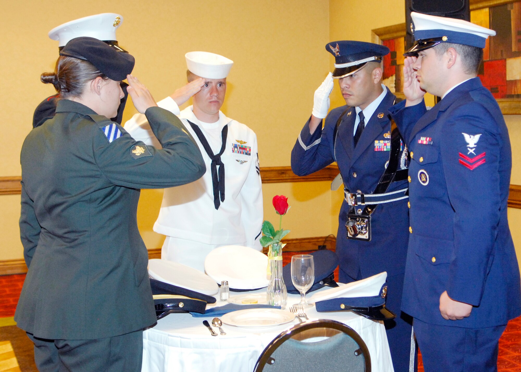 AURORA, Colo. -- Servicemembers from the Army, Marine Corps, Navy, Air Force and Coast Guard salute the Prisoner of War / Missing in Action remembrance table during the Senior NCO Induction Aug. 27. (U.S. Air Force photo by Tech. Sgt. Shirley Henderson)