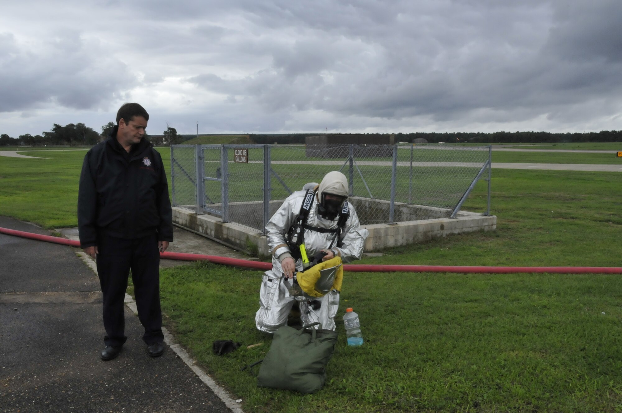 Airman 1st Class Nicholas Lawerence(right), 48th Civil Engineer Squadron firefighter, gets his gear ready while acting as a safety monitor for visiting firefighters from RAF Wattisham while Frank Engall, 48th CES fire safety manager, observes at RAF Lakenheath, England, Aug. 27. This was the first time RAF firefighters trained at Lakenheath. (U.S. Air Force photo/Airman 1st Class Eboni Knox)