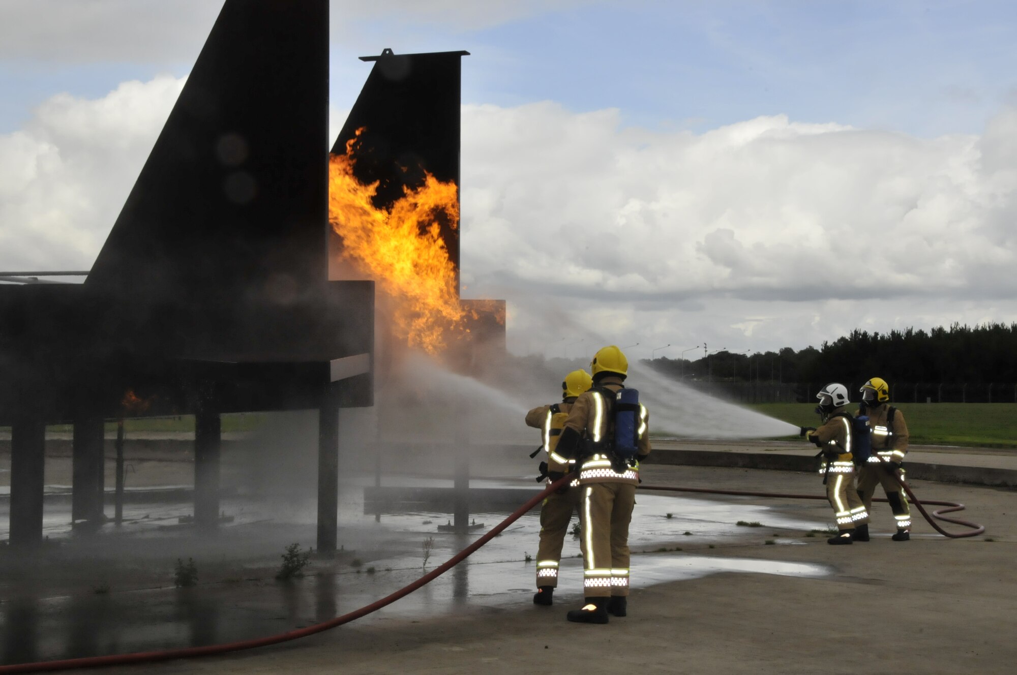 Firefighters from RAF Wattisham fight a controlled propane fire during training with Air Force and MOD firefighters Aug. 27 on RAF Lakenheath, England. The RAF firefighters trained on a mock-up F-15.  (U.S. Air Force photo/Airman 1st Class Eboni Knox)