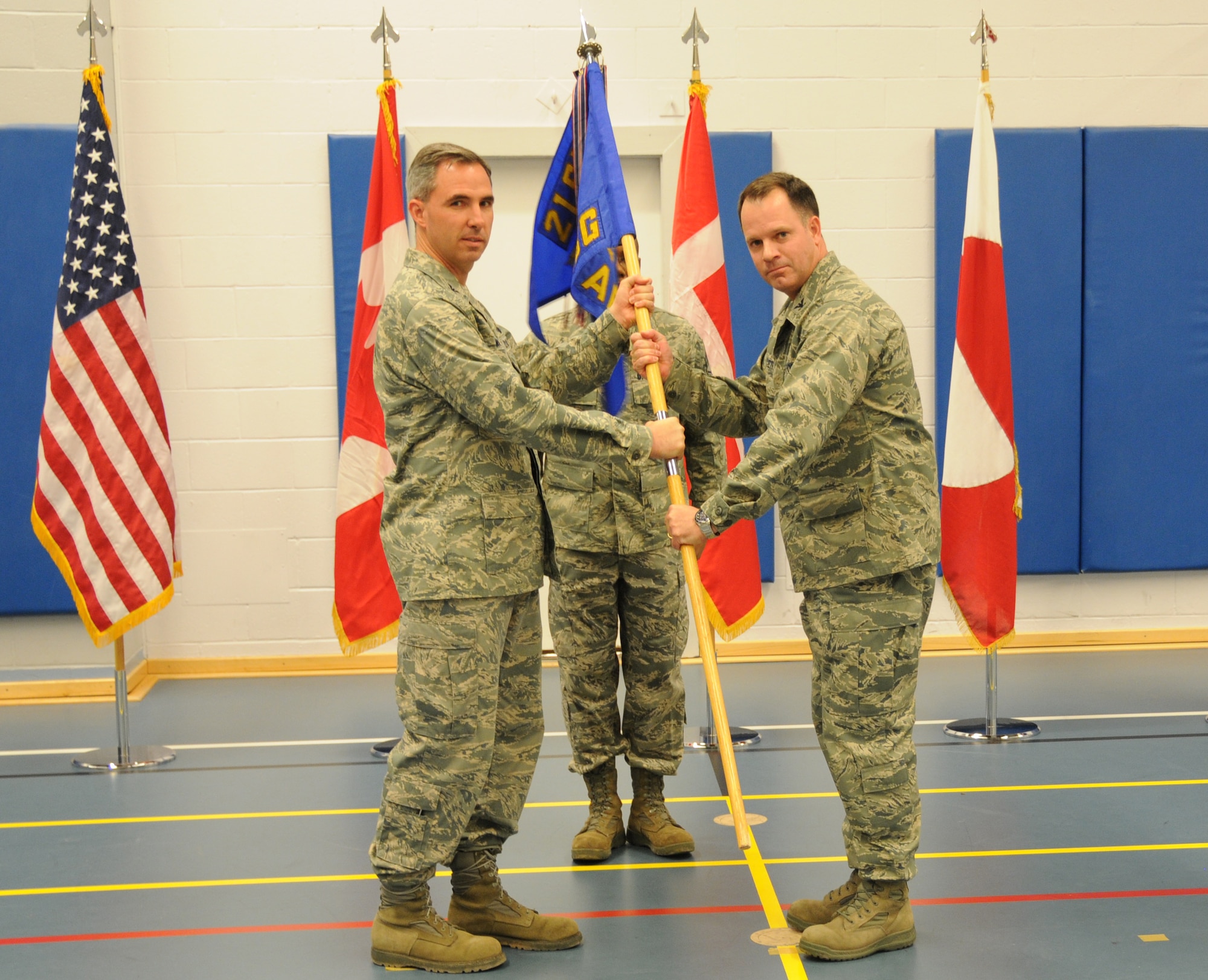 THULE AIR BASE, Greenland -- Col. Mark Allen (right), receives the 821st Air Base Group guidon from Col. Stephen N. Whiting, 21st Space Wing commander, during the group’s change-of-command ceremony at the Dundas fitness center Aug. 12. As the installation commander, Colonel Allen is responsible for the administration and security of the Air Force’s largest overseas and America’s northernmost base comprised of the Thule Defense Area. As the senior U.S. government representative to Greenland, he guides international relations ensuring compliance of all the agreements between the U.S., Danish and Greenlandic governments. He also directs operations of the world’s northernmost deep seaport and the Arctic’s largest airfield and provides full-spectrum base support for about 650 year-round residents. (Air Force photo/Staff Sgt. Sarah Beasley)
