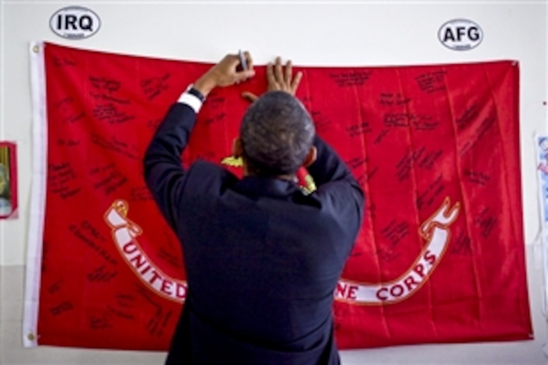 President Barack Obama signs a banner hanging in a room while visiting with wounded warriors at Walter Reed Army Medical Center in Washington, D.C., Aug. 30, 2010.