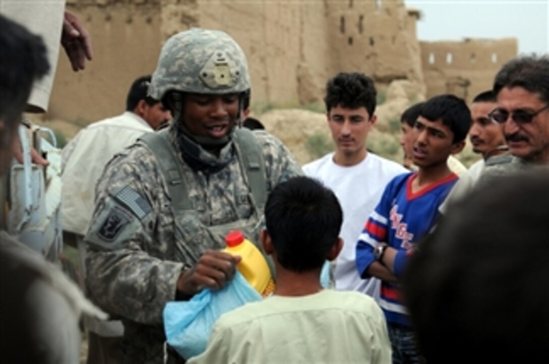 U.S. Army Capt. Terrance McIntosh (left), a civil affairs officer from Headquarters and Headquarters Troop, 1st Squadron, 172nd Cavalry Regiment, distributes supplies in the village of Bashikal in Parwan province, Pakistan, during a humanitarian aid mission on Aug. 25, 2010.  The village was affected by damaging floods.  The aid included bags of rice and cooking oil.  