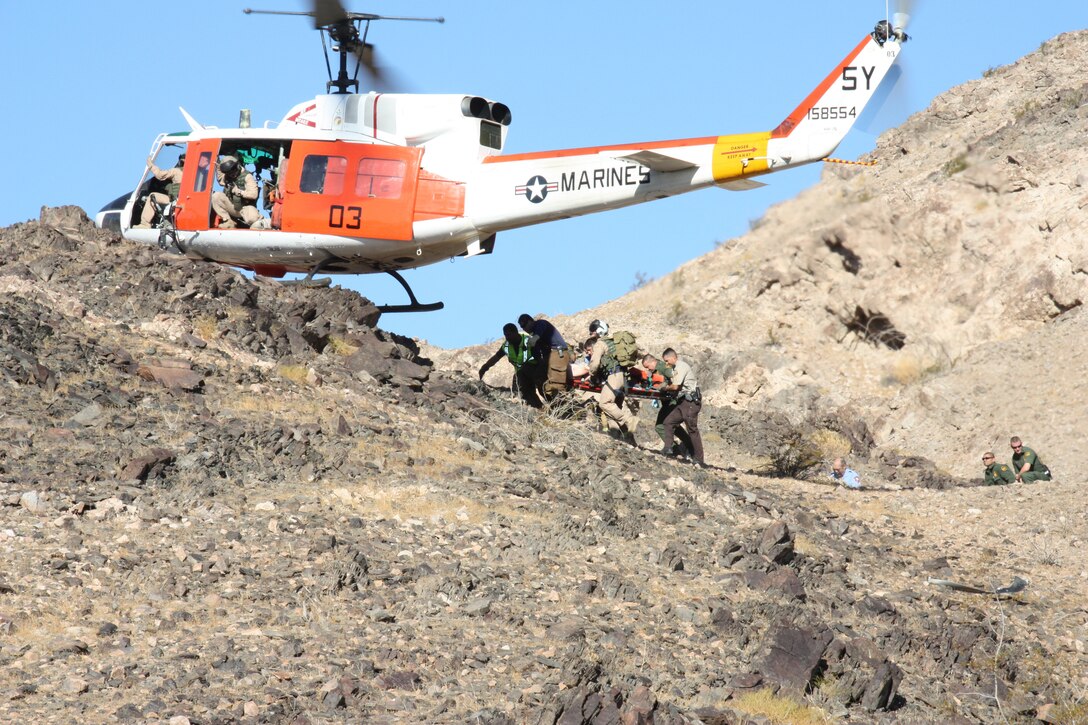 Search and Rescue from the Marine Corps Air Station in Yuma, Ariz., along with local law enforcement personnel, carry the victim of a local plane crash to a SAR HH-1N Huey on Aug. 31, 2010. The victim, Dan Bosser, 57, was transported by SAR to Yuma Regional Medical Center where he received treatment for non-life-threatening injuries. Because of the rough terrain, the pilots were forced to execute a technique referred to as a “101,” in which one landing skid rests on the ground, while the other remains suspended while the rotors are still turning. SAR’s mission is to support various rescue operations within 100 nautical miles of the air station.