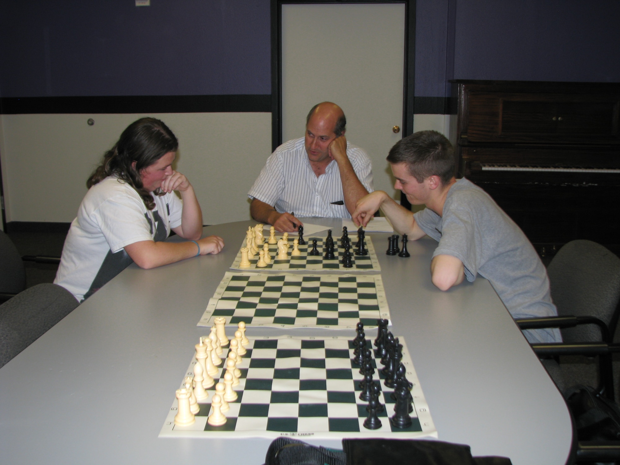 Chess Club: Instructor Matt Mahowald (center) guides students Peggy Perkins (right) and Kyle Kirk (left) through their moves during a lesson. The Chess Club currently meets once a week at the Edwards Teen Center, but will meet more often as the membership grows. The Teen Center is located at the Desert Mall. (Air Force photo by Diane Betzler)