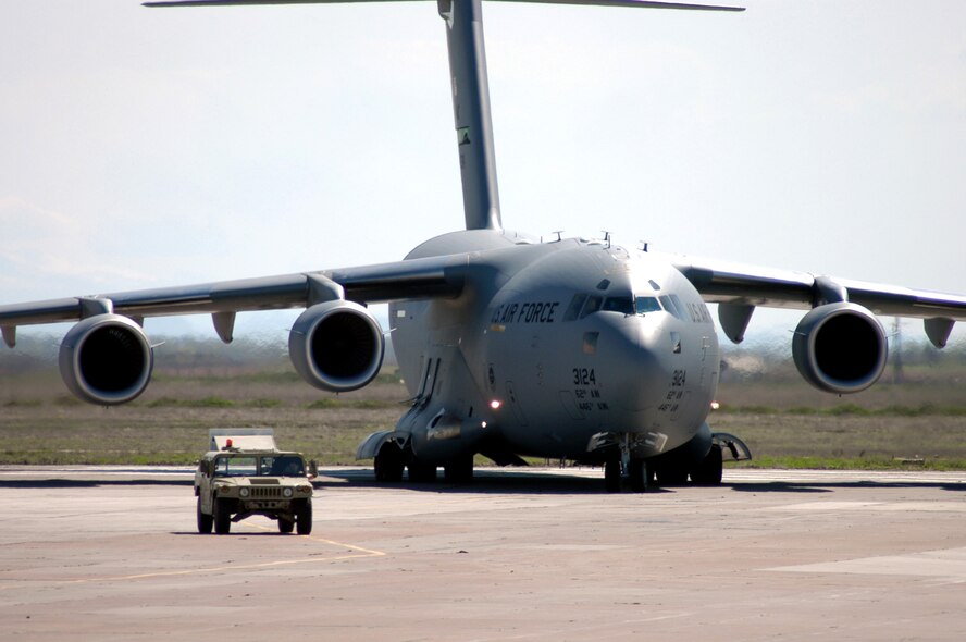 A C-17 Globemaster III from the 62nd Airlift Wing, on deployment from McChord Air Force Base, Wash., follows a High-Mobility Multipurpose Wheeled Vehicle transient alert vehicle to a parking spot during airfield operations at Karshi-Khanabad Air Base, Uzbekistan, on March 20, 2005, during Operation Enduring Freedom. (U.S. Air Force Photo/Master Sgt. Scott T. Sturkol)
