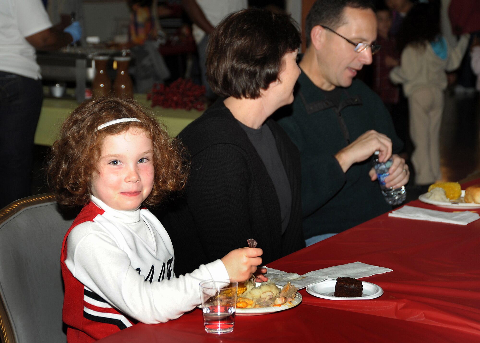Cheerleader Rachel Hermes enjoys a meal with her parents, Lt. Col. Doug and Ruth Hermes, at the Family Feast Pot Luck, Nov. 18.  Los Angeles Air Force Base, 61st Force Support Squadron and Youth Programs Office hosted the event to kick off the Thanksgiving holiday and provided ham and turkey to the many side dishes brought by family members. (Photo by Joe Juarez)

