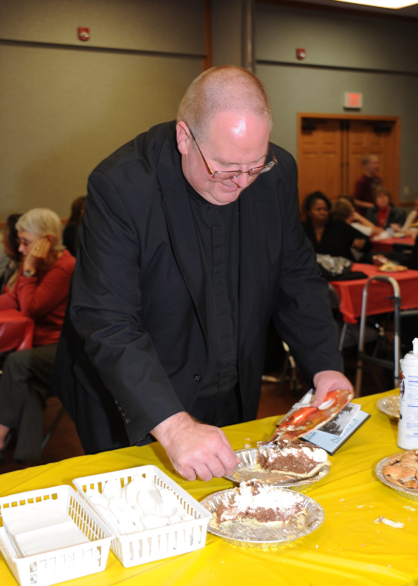 Father John Hotze, Catholic priest, cuts a piece of pie after the annual Ecumenical Thanksgiving Service at the base chapel Nov. 23, 2010, McConnell Air Force Base, Kan. Father Hotze gave a non-specific religious sermon during the service. Servicemembers participated in a pie social after the Thanksgiving event. (U.S. Air Force photo/Airman 1st Class Katrina M. Brisbin)  