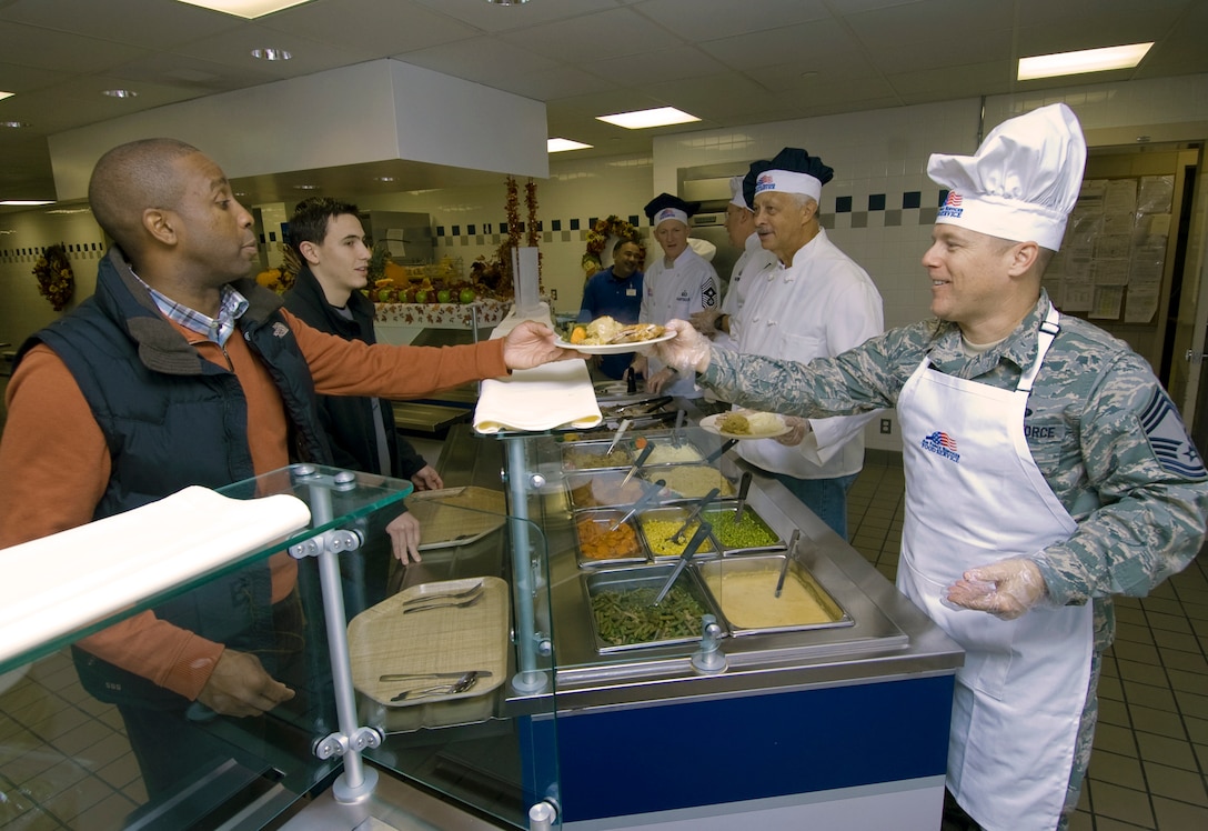 Chief Master Sgt. Gary Shedenhelm, 844th Communications Group chief enlisted manager, right, serves Robert Yarbrough, 11th Wing director of staff, left, at the Freedom Hall Dining Facility Thanksgiving Day. (U.S. Air Force photo/Bobby Jones)