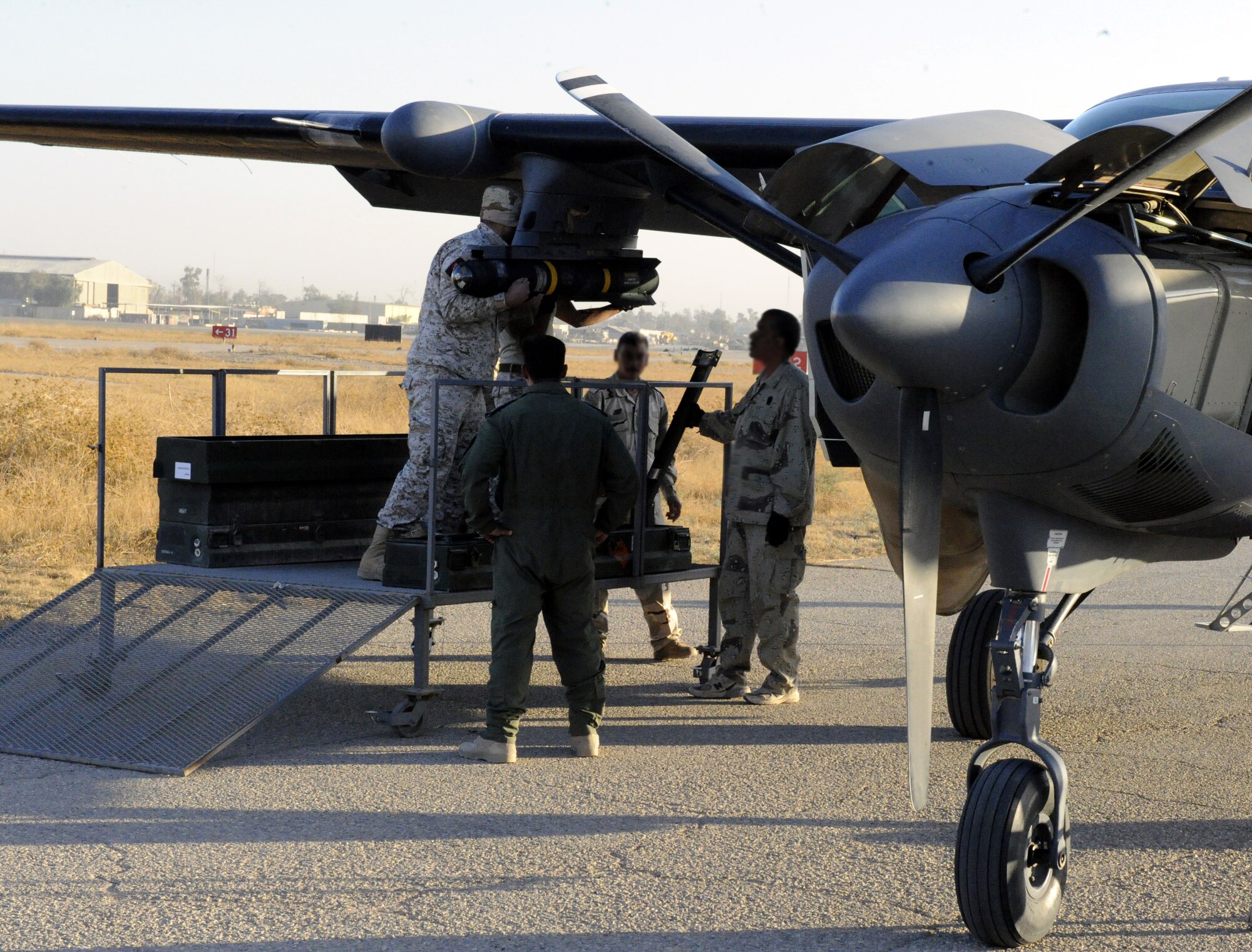 An Iraqi Air Force maintenance officer briefs weapons load checklist procedures to U.S. Air Force Air Advisors TSgt  Joseph Sparlin and Maj Matthew Goddard, before a Hellfire missile launch training mission, Nov. 8, 2010. An all-Iraqi aircrew scored a direct-hit at of their target on the Aziziyah Range, south of Baghdad, destroying the target in their second-ever launch of a Hellfire missile.  Iraqi Airmen have trained continuously for the Hellfire mission, mastering the weapons load, target attack and airmanship skills necessary to maintain proficiency since completing their first Hellfire launch in 2009, also resulting in a direct hit of a training target.  U.S. Air Force Air Advisors of the 521st Air Expeditionary Advisory Squadron at Kirkuk work shoulder-to-shoulder as partners in the effort. (U.S. Air Force photo by Senior Master Sgt. Dean J. Miller)