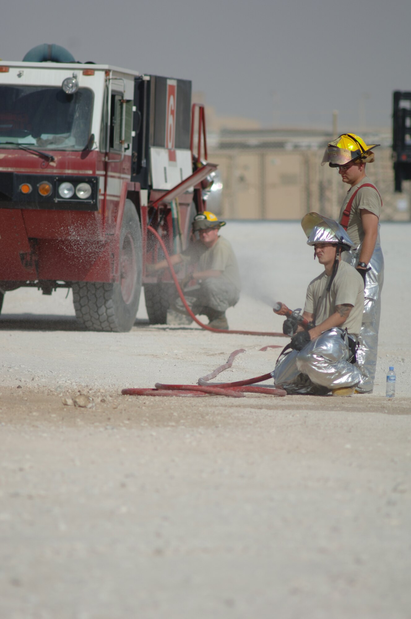 SOUTHWEST ASIA - Senior Airman James Demmeritt, back, controls water pressure, while Staff Sgt Paul Dodds, front, and  Airman First Class Paul Rea prepare the hose to be used to simulate decontaminating a casualty here, Oct. 28, during an interoperability exercise. (U.S. Air Force photo/Tech. Sgt. Kimberly Spinner)