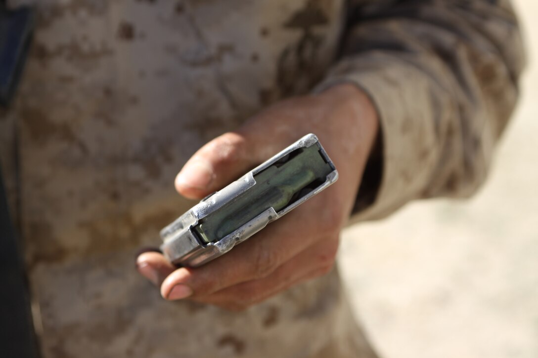 Recruit Ben J. Stocker, Platoon 3226, Company K, holds out his empty magazine to show his drill instructors he has no live rounds left after completing a defense firing course at the Crucible. The recruits are searched after every live fire exercise to ensure that no rounds are unaccounted.