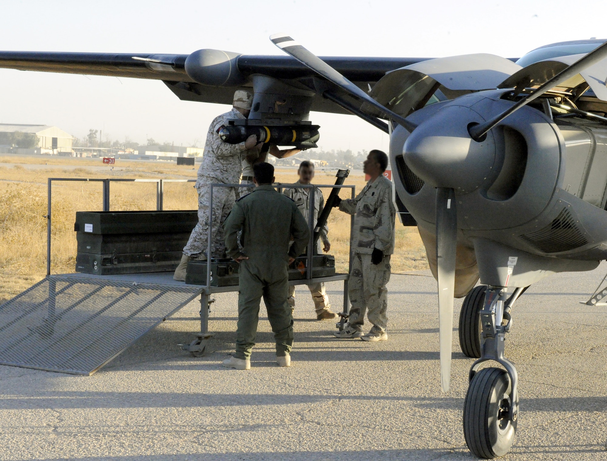 An Iraqi air force maintenance officer briefs weapons load checklist procedures to Tech. Sgt. Joseph Sparlin and Maj. Matthew Goddard, before a Hellfire missile launch training mission Nov. 8, 2010, in Iraq. An all-Iraqi aircrew scored a direct hit of their target on the Aziziyah Range, south of Baghdad, destroying the target in their second launch of a Hellfire missile. Iraqi airmen have trained continuously for the Hellfire mission, mastering the weapons load, target attack and airmanship skills necessary to maintain proficiency since completing their first Hellfire launch in 2009, also resulting in a direct hit of a training target. Sergeant Sparlin and Major Goddard are Air Force air advisers with the 521st Air Expeditionary Advisory Squadron at Kirkuk work. (U.S. Air Force photo/Senior Master Sgt. Dean J. Miller) 