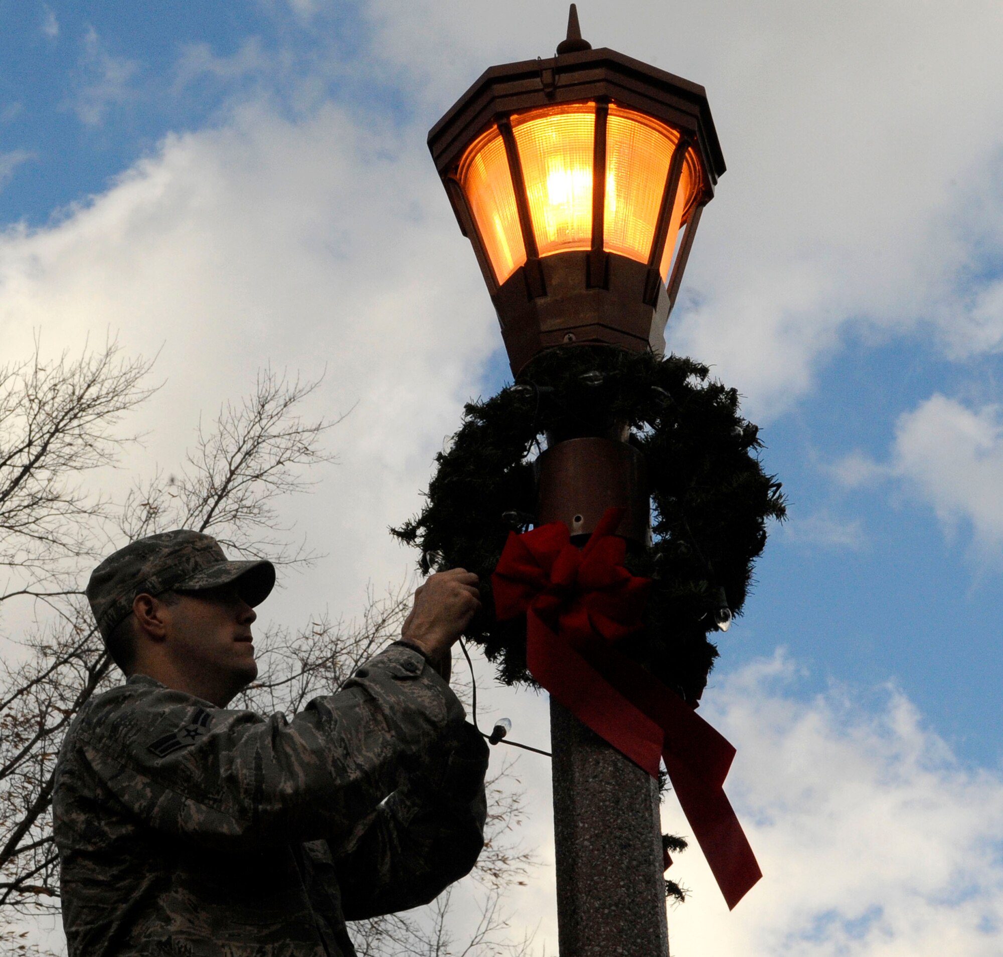 LANGLEY AIR FORCE BASE, Va.—Airman 1st Class Jared Clark, 633d Civil Engineer Squadron electrical systems apprentice, adjusts a holiday wreath wrapped around a light pole Dec. 1. The Civil Engineer Squadron went around the installation decorating to prepare the base for the holiday season. (U.S. Air Force photo/Staff Sgt. Dana Hill)(RELEASED)