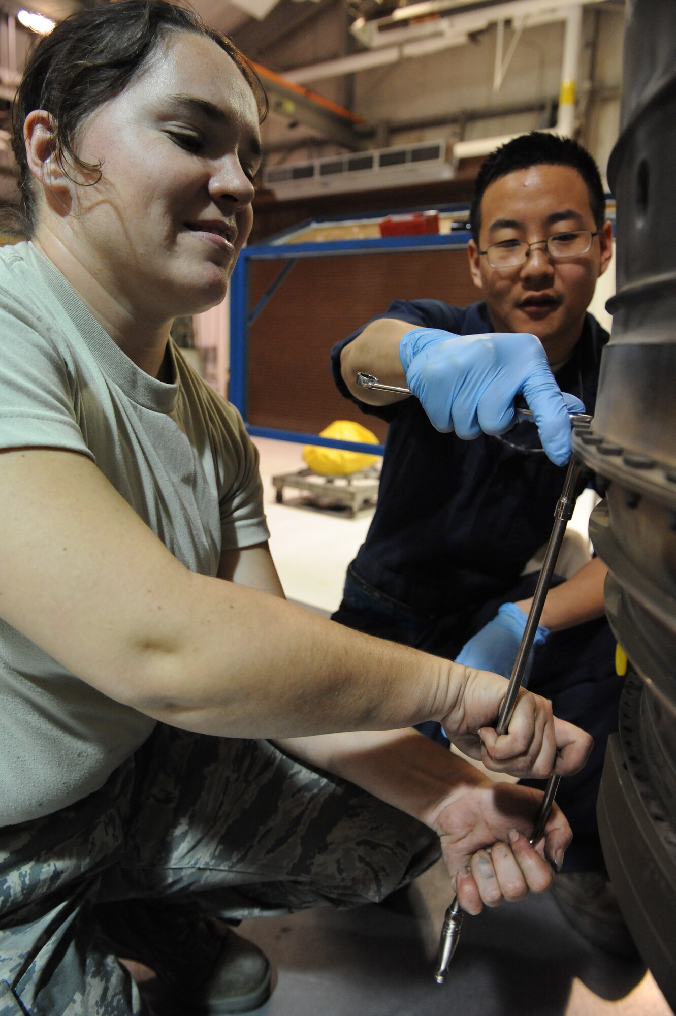 SEYMOUR JOHNSON AIR FORCE BASE, N.C. -- Senior Airman Jeffrey Jin holds a bolts head to prevent stripping as Staff Sgt. Edith Bartolomeo loosens it on an engine turbine exhaust case here, Nov. 30, 2010. The engine exhaust case is attached to the low pressure turbine and houses the number five bearing area and straightens out the air flow from the core engine module. Airman Jin and Sergeant Bartolomeo are both 4th Component Maintenance Squadron jet engine mechanics. Airman Jin is from Diamond Bar, Calif. and Sergeant Bartolomeo is from Kill Devil Hills. (U.S. Air Force photo/Staff Sgt. Courtney Richardson)