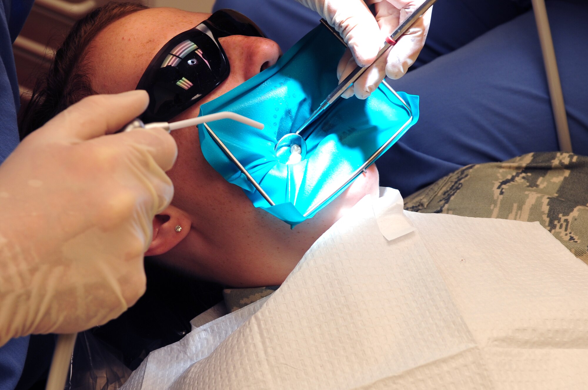 MOODY AIR FORCE BASE, Ga.-- Dr. (Capt.) Edward Trouy, 23rd Aeromedical Dental Squadron dentist, uses a dental mirror to reflect light on the teeth of  Airman 1st Class Faith Crawford, 824th Base Defense Squadron,  during a dental filling procedure Nov. 24. A dental filling is a type of restorative dentistry treatment used to repair minimal tooth fractures, tooth decay or otherwise damaged surfaces of the teeth. (U.S. Air Force photo/Senior Airman Stephanie Mancha)(RELEASED)