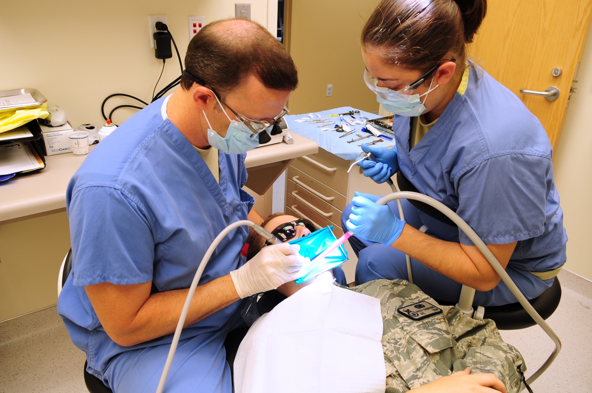 MOODY AIR FORCE BASE, Ga.-- Dr. (Capt.) Edward Trouy, 23rd Aeromedical Dental Squadron dentist, and Airman 1st Class Natalie Hellwig, 23rd AMDS dental assistant, perform a dental filling procedure on Airman 1st Class Faith Crawford, 824th Base Defense Squadron, Nov.24. A dental filling is a type of restorative dentistry treatment used to repair minimal tooth fractures, tooth decay or  damaged surfaces of the teeth. (U.S. Air Force photo/Senior Airman Stephanie Mancha)(RELEASED)