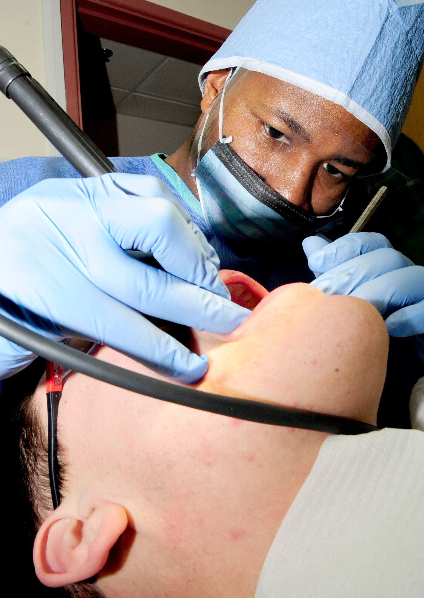 RAF MILDENHALL, England -- Senior Airman Jonahthan Davis, 48th Dental Squadron dental assistant, uses a cavitron water pick to remove plaque from a patient's teeth during his yearly cleaning Dec. 2, 2010. The water pick is used to remove heavier buildups of plaque from the teeth and to clean the hard to reach places. (U.S. Air Force photo/Senior Airman Ethan Morgan)