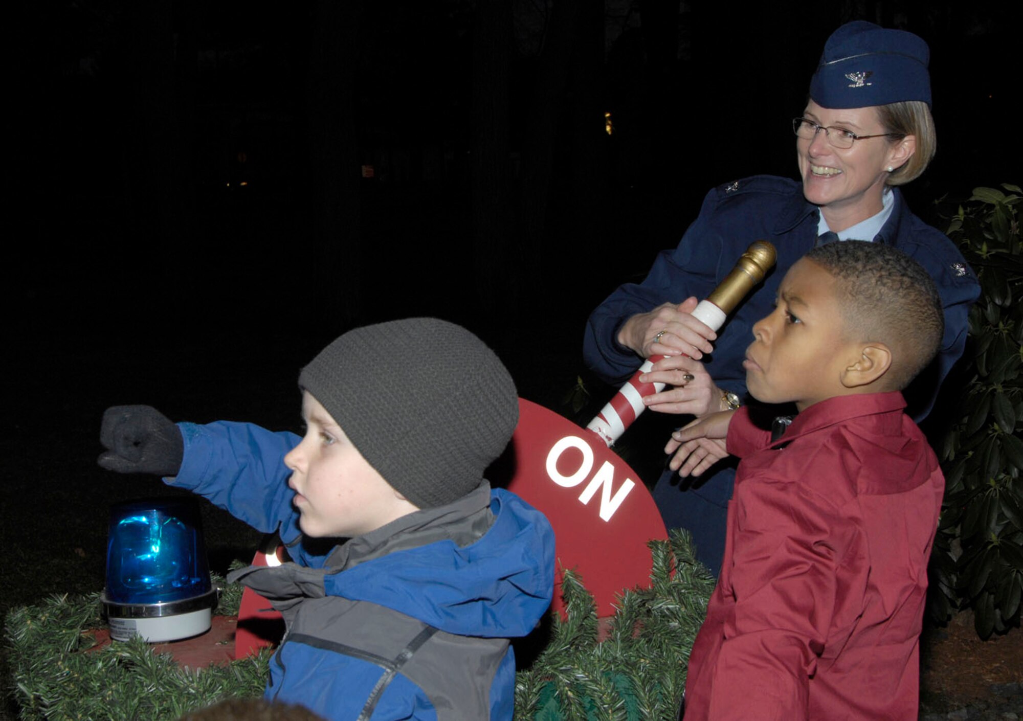 HANSCOM AIR FORCE BASE, Mass. – Liam Lasse and Troy Gulley Jr. help Col. Stacy L. Yike (right), 66th Air Base Group commander, flip the light switch from off to on during the Tree Lighting Ceremony at the Base Chapel on Nov. 29. The ceremony signaled the beginning of the holiday season on base. (U.S. Air Force photo by Linda LaBonte Britt)