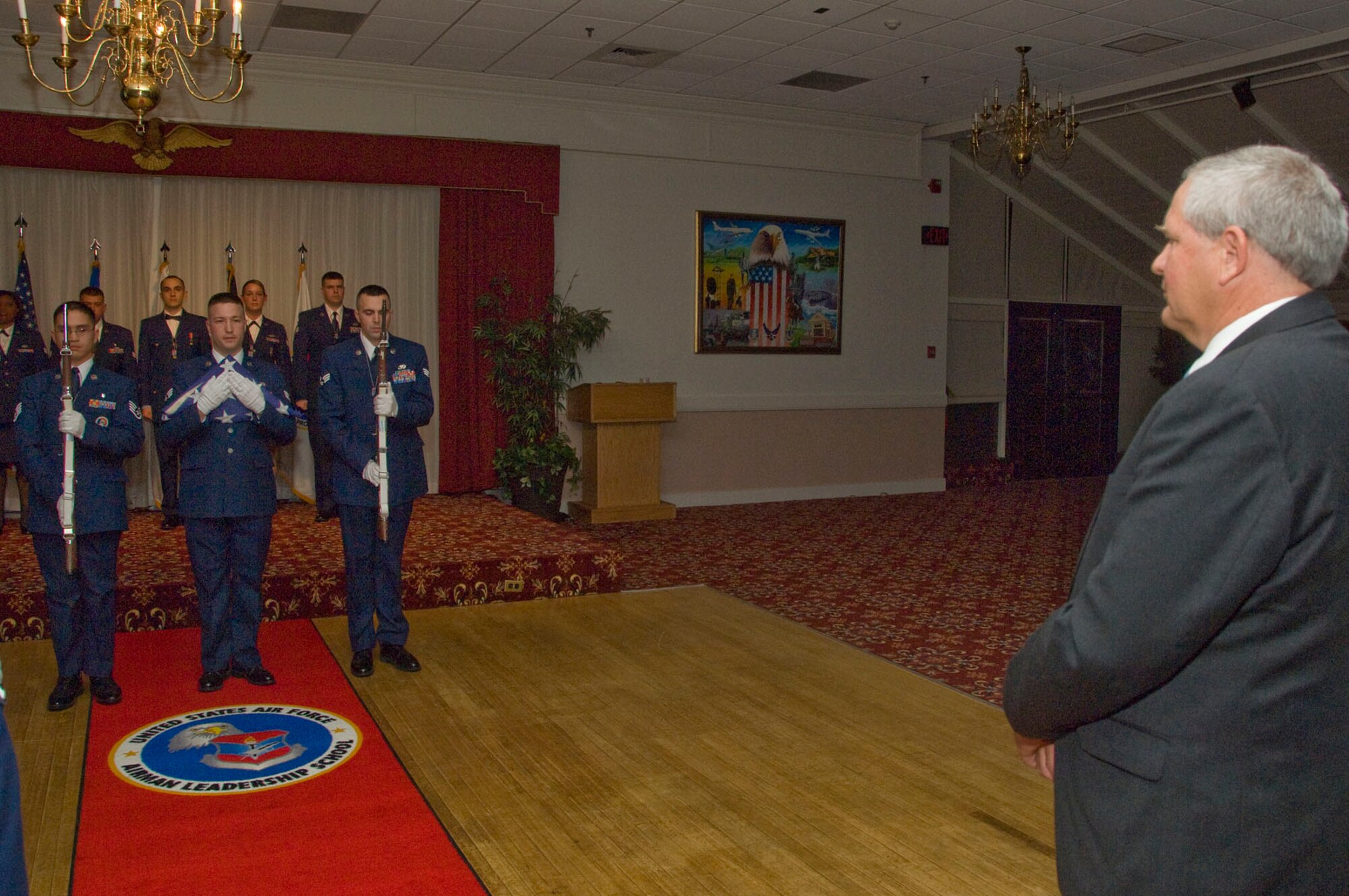 HANSCOM AIR FORCE BASE, Mass. – Staff Sgt. Harold A. Pastoral (left), Senior Airman Jamie A. Moore and Senior Airman Brent M. Tompkins prepare to present a flag to Cory Etchberger (right) on behalf of the 66th Air Base Group and the class during the Airman Leadership School Class 11A graduation at the Minuteman Club on Nov. 19. Cory Etchberger served as the special guest during the ceremony. His father was Chief Master Sgt. Richard L. Etchberger, who was posthumously awarded the Medal of Honor for his actions in a remote site in Laos in 1968. (U.S. Air Force photo by Lance Beebe)