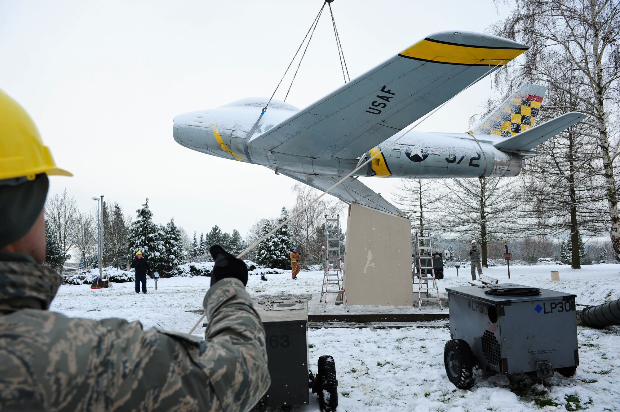 U.S. Air Force personnel from the 86th Maintenance Squadron help lower a F-86F Sabre jet after it's removal from a concrete mount, Sembach Annex, Germany, Nov. 30, 2010. The aircraft will be refurbished and redisplayed at Ramstein Air Base Hardened Aircraft Shelter as a representative F-86F aircraft from the 86th Fighter Bomber Wing. (U.S. Air Force photo by Airman 1st Class Brea Miller)