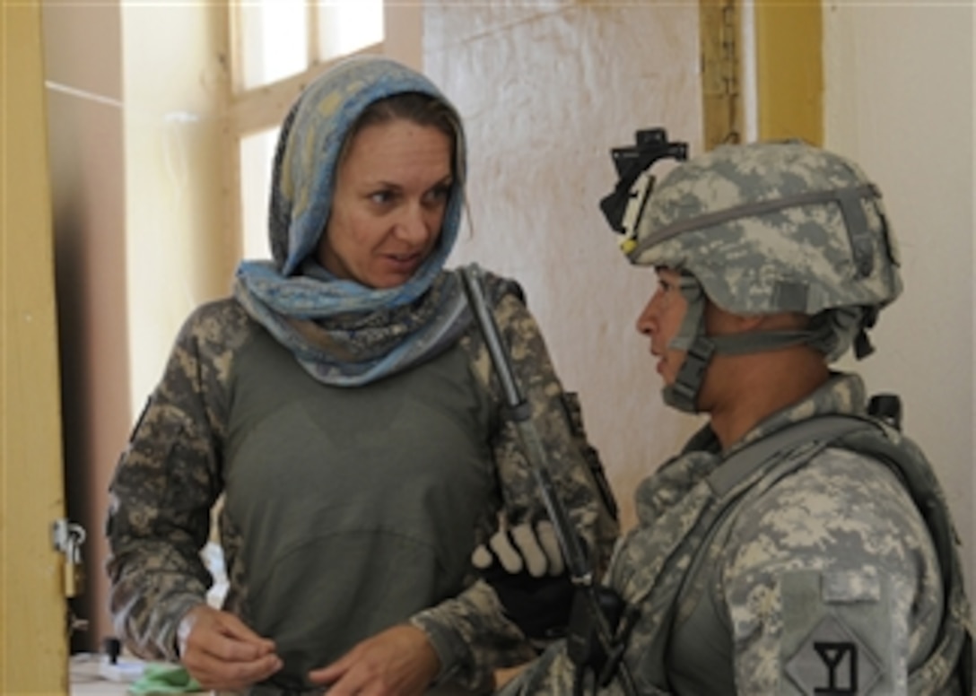U.S. Navy Cmdr. Karen Griffith (left), executive officer of the Nuristan Provincial Reconstruction Team, updates Sgt. Keith Radcliffe, a Provincial Reconstruction Team security force member, on the progress of the district development meeting in Nurgaram, Nuristan province, Afghanistan, on Nov. 23, 2010.  The Nuristan Provincial Reconstruction Team helped the Afghan government improve security and increase infrastructure capacity in the country.  