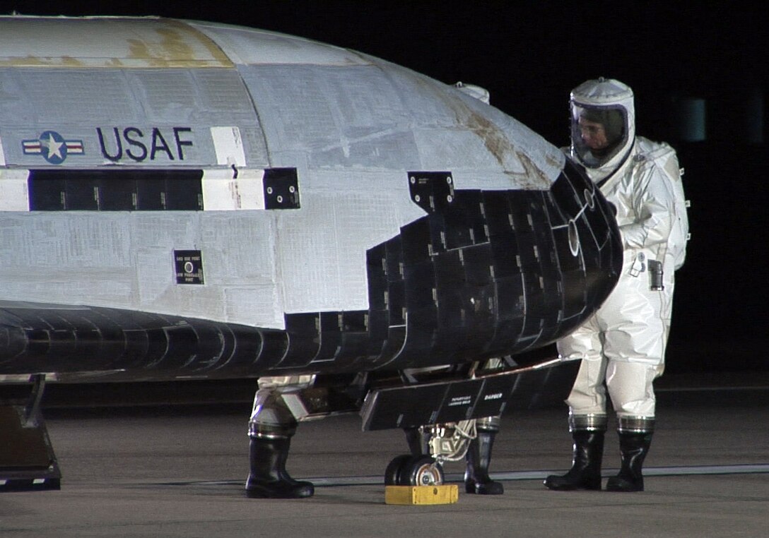 The X-37B Orbital Test Vehicle sits on the runway at Vandenberg Air Force Base, Calif., Dec. 3, 2010, during post-landing operations. Personnel in self-contained atmospheric protective ensemble suits are conducting initial checks on the vehicle and ensuring the area is safe. The X-37B launched April 22 from Cape Canaveral, Fla., allowing teams to conduct on-orbit experiments for more than 220 days during this first mission. (U.S. Air Force photo/Michael Stonecypher)