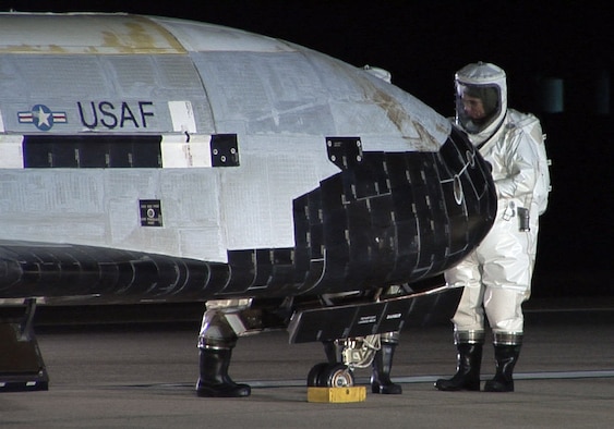 The X-37B Orbital Test Vehicle sits on the runway at Vandenberg Air Force Base, Calif., Dec. 3, 2010, during post-landing operations. Personnel in self-contained atmospheric protective ensemble suits are conducting initial checks on the vehicle and ensuring the area is safe. The X-37B launched April 22 from Cape Canaveral, Fla., allowing teams to conduct on-orbit experiments for more than 220 days during this first mission. (U.S. Air Force photo/Michael Stonecypher)