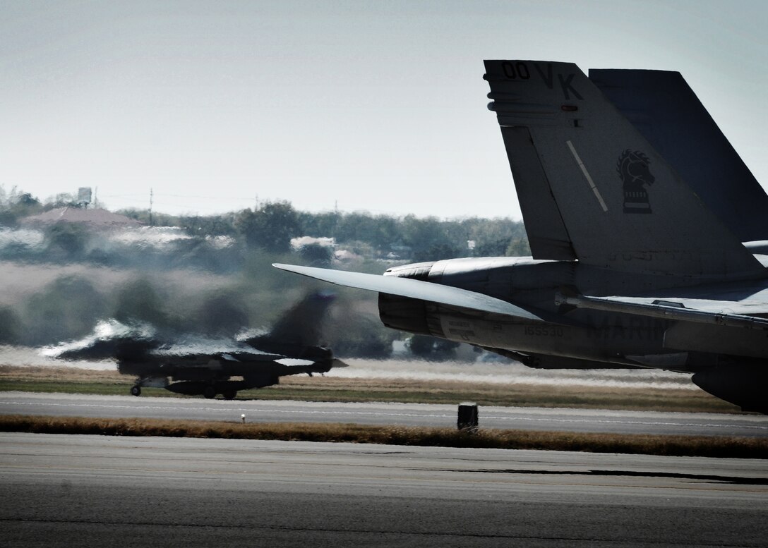 The jet wash from an F/A-18 Hornet from Marine Corps Air Station Miramar, California, blurs the view of an F-16 assigned to the Texas Air National Guard's 149th Fighter Wing. The two units participated in a joint training exercise at Kelly Field, Lackland Air Force Base, Texas, December 3, 2010.
(U.S. Air Force photo/Staff Sgt. Eric L. Wilson)