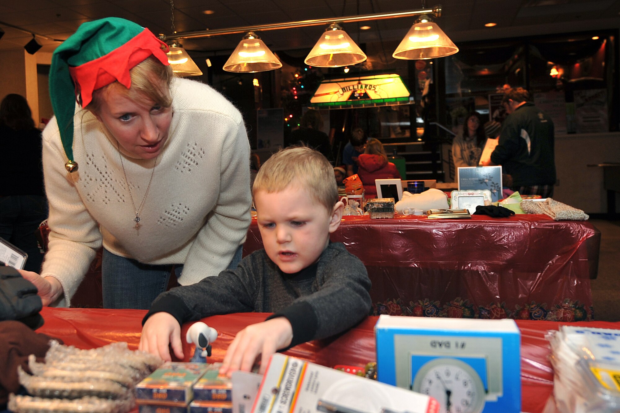 OFFUTT AIR FORCE BASE, Neb. - Mary Jensen, wife of the 55th Wing vice commander Col. William Jensen, helps Cohen Wiebers pick out a gift for his father, Army Staff Sgt. Chad Wiebers, during the tree lighting and holiday events inside the Community Activity Center Dec. 2. This annual event provides Team Offutt member and their families a fun environment to share their joy and give presents to their love ones this Christmas season.  U.S. Air Force Photo by Charles Haymond