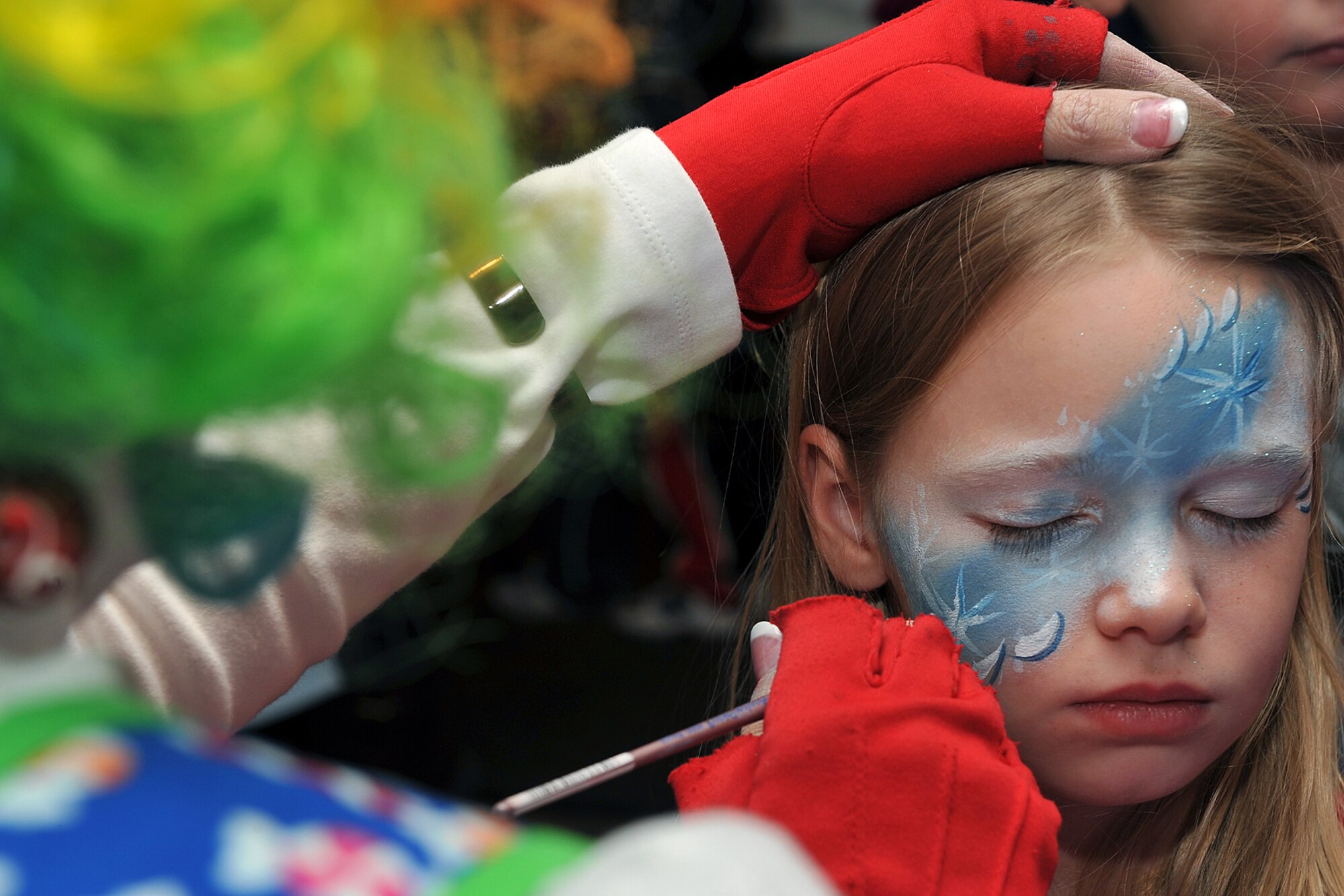OFFUTT AIR FORCE BASE, Neb. ? Sara Voorhees, daughter of Capt. Corey Voorhees, gets her face painted by Donna Trout, also known as Rainbow Trout the clown, during the tree lighting and holiday events inside the Community Activity Center Dec. 2. This annual event provides Team Offutt member and their families a fun environment to share their joy and give presents to their love ones this Christmas season.  U.S. Air Force Photo by Charles Haymond