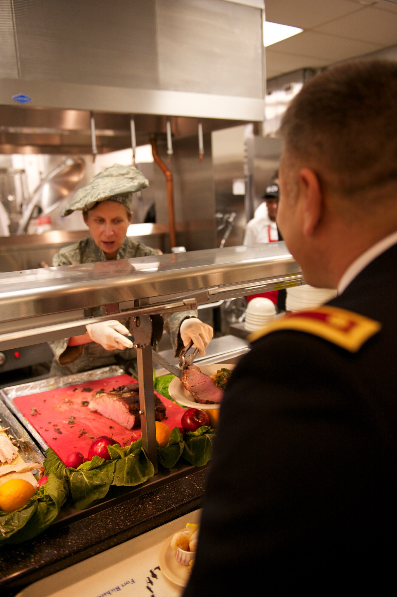 JOINT BASE ELMENDORF-RICHARDSON, Alaska -- Chief Master Sgt. Lisa Kuehnl, 673d Air Base Wing command chief master sergeant, serves a cutlet to Army Maj. Ronald Eggelston, HHC, 3rd Maneuver Enhancement Brigade, Thanksgiving, at the Gold Rush Inn Dining Facility. (Photo by David Bedard/JBER PAO)
