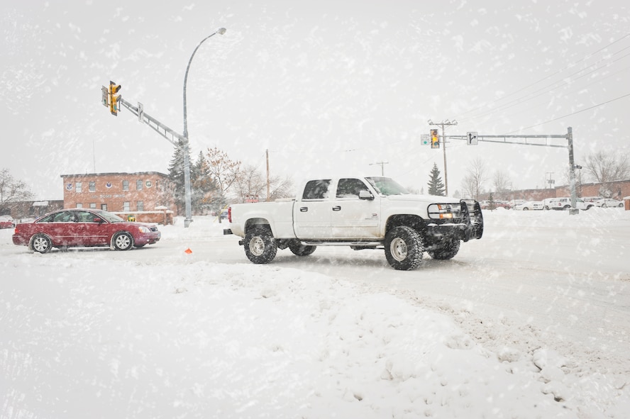 MINOT AIR FORCE BASE, N.D. -- Vehicles are seen driving by the 5th Bomb Wing headquarters building here Dec. 3 as snow flies creating hazardous road conditions. (U.S. Air Force photo illustration/Senior Airman Benjamin Stratton)