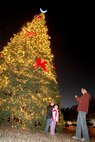 Staff Sgt. Greg Johnson, 321st Training Squadron, takes a photo of his daughter and his daughter's friend in front of the base Christmas tree at the Gateway Club Dec. 1. During the tree lighting ceremony, the Air Force Band of the West presented a special musical selection and the Lackland Performing Arts Group performed in the club ballroom. (U.S. Air Force photo/Robbin Cresswell)