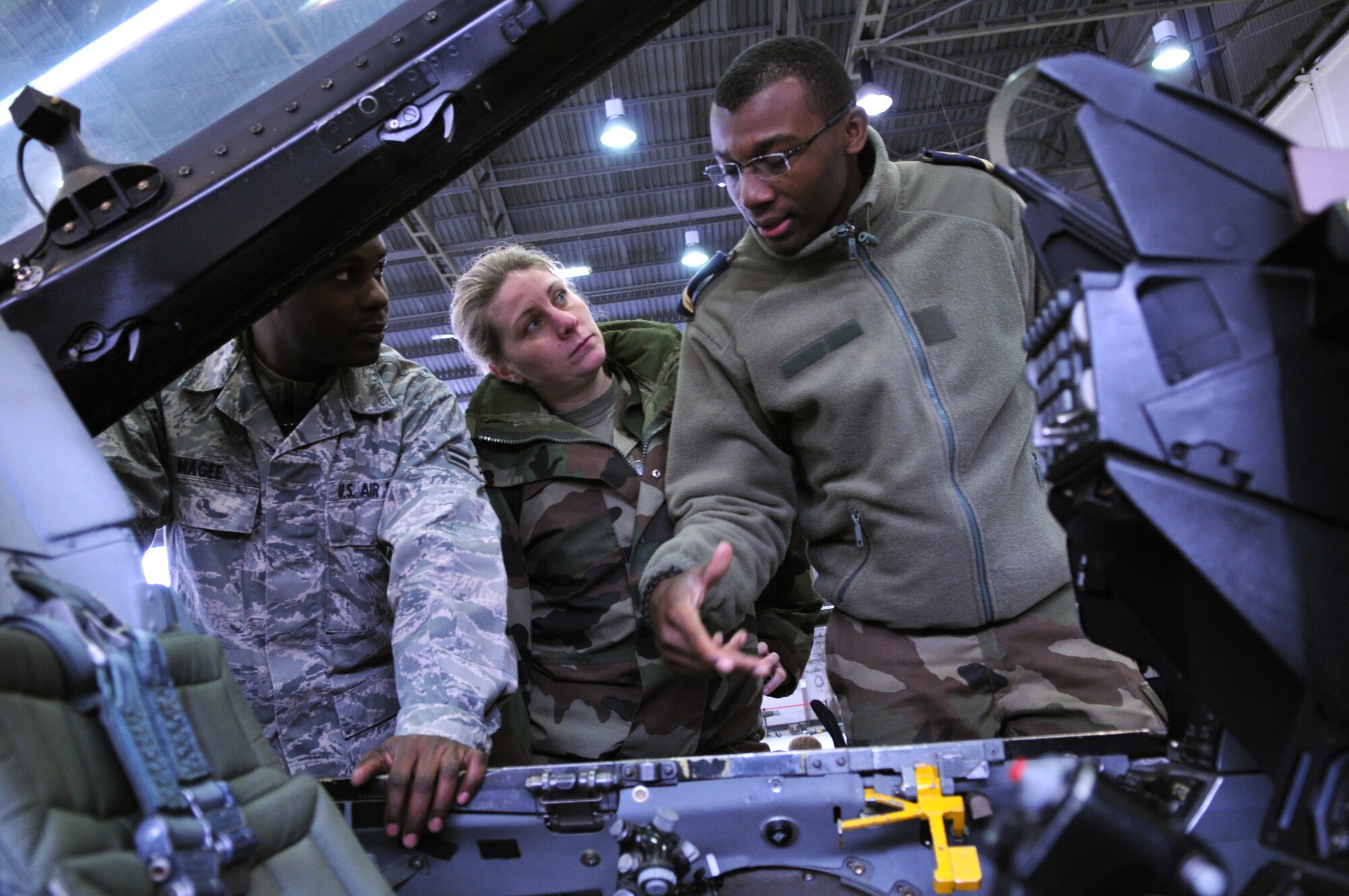 SPANGDAHLEM AIR BASE, Germany – Airman 1st Class Myrondous Magee, 480th Aircraft Maintenance Unit maintainer, shows French Sgt.-Chef Thibaud Gaelle and French Sgt. Valery Hand the instrument panel in the cockpit of an F-16 Fighting Falcon during a NATO visit Dec. 2. Members of NATO Headquarters Allied Air Command at Ramstein Air Base, Germany, visited the 52nd Fighter Wing to familiarize themselves with an American fighter wing and how it operates. (U.S. Air Force photo/Airman 1st Class Matthew B. Fredericks)