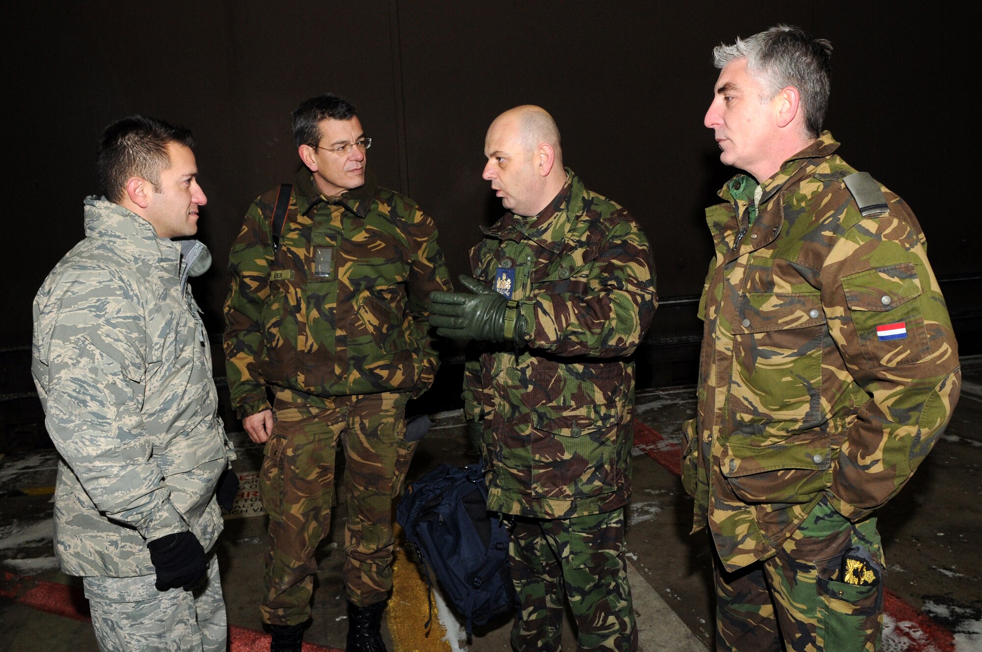 SPANGDAHLEM AIR BASE, Germany – United Kingdom Warrant Officer Peter Polidano speaks with U.S. Air Force Master Sgt. John Flores, 81st Aircraft Maintenance Unit production superintendent, and Dutch air force Warrant Officers André Boer and Wen Hendriks during a NATO visit Dec. 2. Members of NATO Headquarters Allied Air Command at Ramstein Air Base, Germany, visited the 52nd Fighter Wing to familiarize themselves with an American fighter wing and how it operates. (U.S. Air Force photo/Airman 1st Class Matthew B. Fredericks)