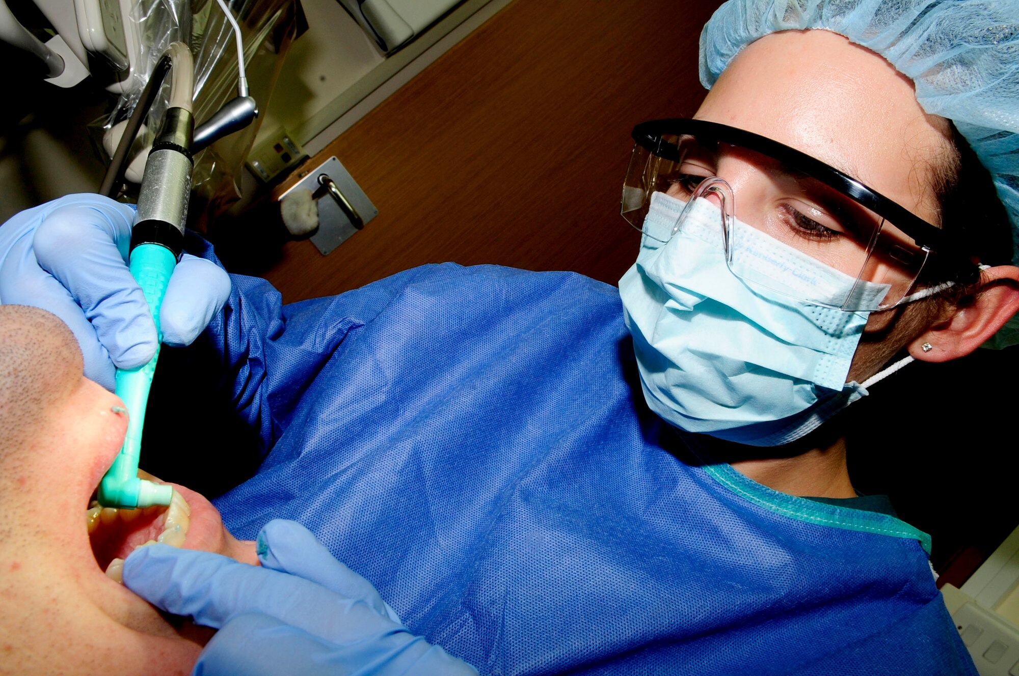 RAF MILDENHALL, England -- Senior Airman Kristi Santiago, 48th Dental Squadron dental assistant, uses a prophy angle to polish a patient's teeth during his yearly cleaning Dec. 2, 2010.  The polisher is used to brush away any excess plaque and give the teeth a more thorough cleaning than a consumer grade toothbrush can provide. (U.S. Air Force photo/Senior Airman Ethan Morgan) 