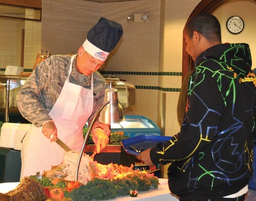 Serving a holiday meal at the Vanwey Dining Facility on Thanksgiving is an annual tradition by Tinker Air Force and Navy officer and enlisted leadership.  Thanking Airmen, Sailors and retirees for their service Nov. 25, Maj. Gen. David Gillett carves turkey for a young hungry diner. More than 500 Airmen and their families enjoyed the holiday feast hosted by 72nd Force Support Squadron and base leaders. (Air Force photo by Liz Choate)