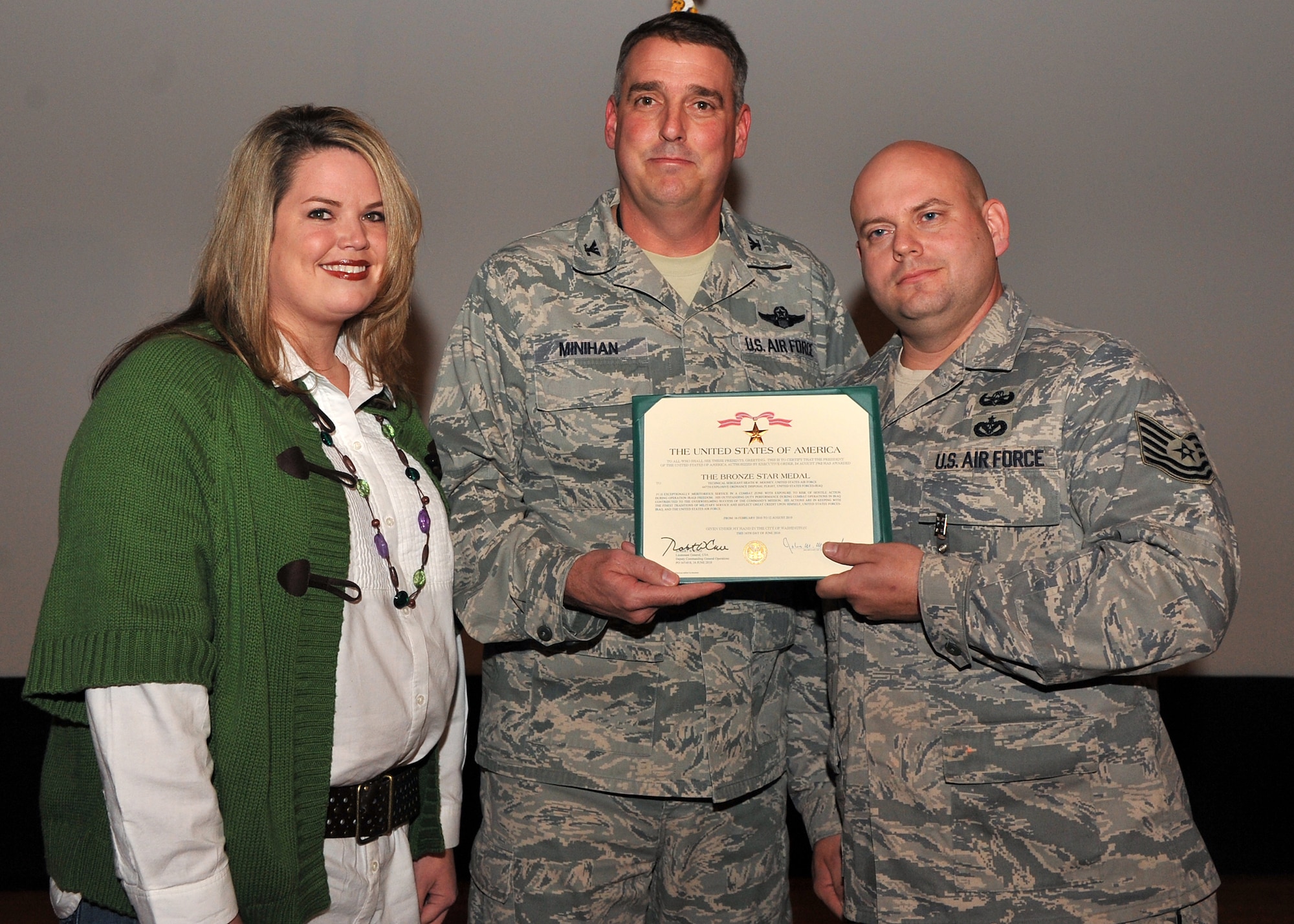 Col. Mike Minihan, 19th Airlift Wing commander, presents Tech. Sgt.  Heath Mooney, 19th Explosive Ordnance Disposal team leader, with his wife Emily (left) with the Bronze Star Medal here Dec. 2, 2010, at Little Rock Air Force Base, Ark.  Sergeant Mooney distinguished himself by exceptionally meritorious service to the United States as EOD Team Leader, 447th Explosive Ordnance Disposal Flight during Operation Iraqi Freedom. Sergeant Mooney led his team on 59 missions during his deployment to Camp Taji, Iraq, directly supporting Army operations. His team destroyed 8,550 ordnance items, slowing the enemy’s ability to make and place improvised explosive devices. (U.S. Air Force photo by Senior Airman Gul Crockett)