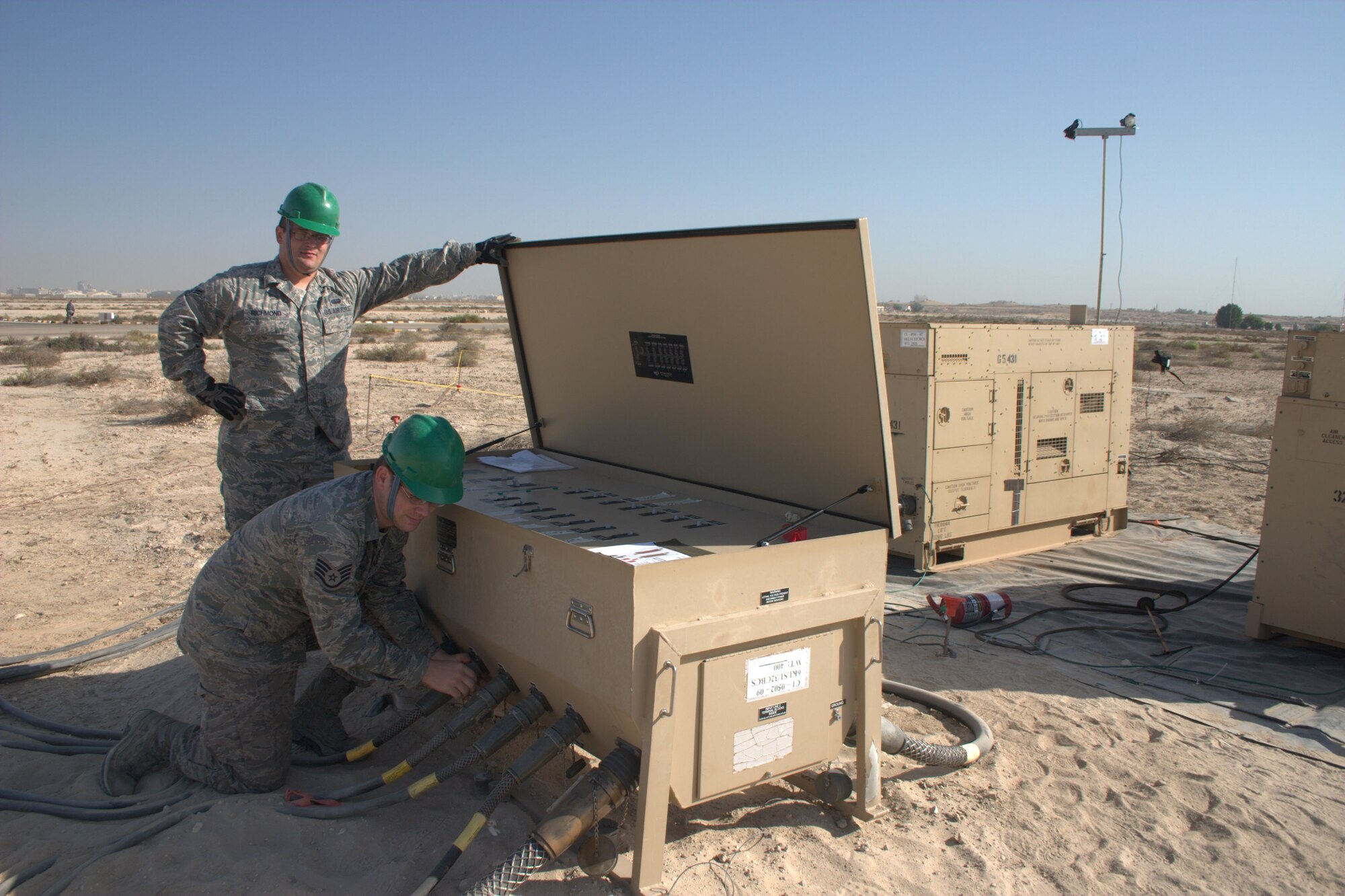 Staff Sgt. Zachary Monson checks an electrical connection before applying power to the grid while Airman 1st Class Seth Richmond assists.