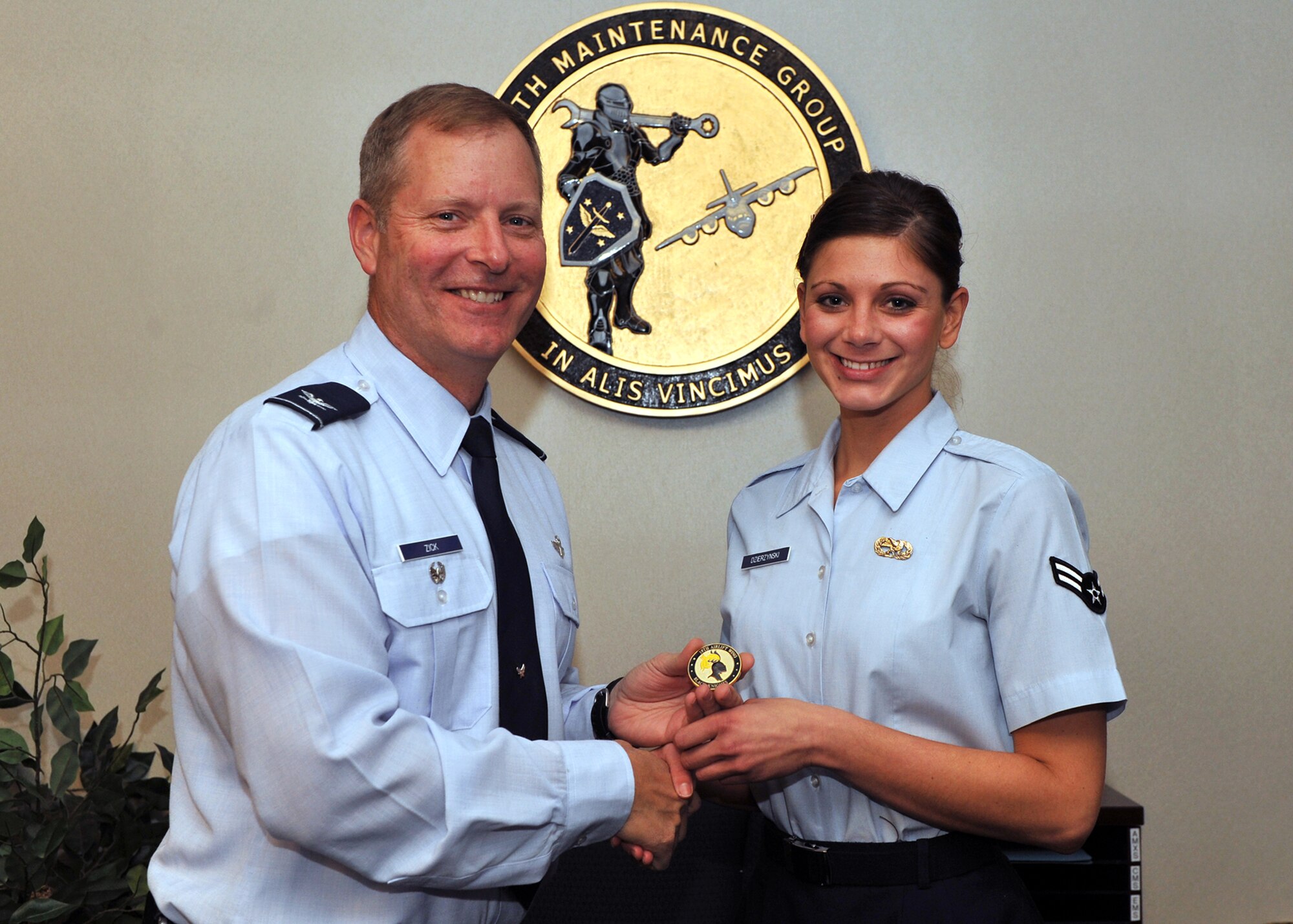 Col. Michael Zick (left), 19th Airlift Wing vice commander, presents a coin Nov. 29, 2010, to Airman 1st Class Amanda Dzierzynski, a 19th Maintenance Operations Squadron database analyst, for her selection as the Combat Airlifter of the Week at Little Rock Air Force Base, Ark. Airman Dzierzynski built a six-month discrepancy study for Little Rock C-130s and provided group leaders with critical information for decision making. (U.S. Air Force photo by Senior Airman Gul Crockett)