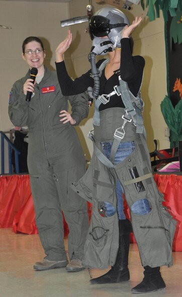 LAUGHLIN AIR FORCE BASE, Texas—First Lt. Heather Tevebaugh, a 47th Flying Training Wing aerospace physiologist, uses Jessica Faz, a teacher at Irene C. Cardwell Elementary, as a demonstration subject on how the gear pilots wear keeps them safe in the plane. Lieutenant Tevebaugh was part of a presentation on Dec. 1 at Cardwell elementary school teaching students about the importance of science and technology. (U.S. Air Force photo by 2nd Lt. Ashley Wolfe) 